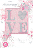 This image shows a romantic anniversary card whose design captures the gentle, enduring warmth of a long relationship, much like an evening spent wandering the quiet streets of Kingston Vale together. At the centre, the word "LOVE" is presented in large, raised letters that glimmer with a frosting of fine glitter. The lettering blends blush pink, pearlescent white, and subtle silver accents, giving a soft yet radiant shine whenever light falls across the surface. Under a fingertip, the glittery embossing would feel lightly textured and inviting, turning the simple act of opening the card into a small, sensory pleasure. Surrounding this central word, a series of stylized blossoms and curling leaves spreads delicately across a muted pink background. The flowers appear almost hand-drawn, with thin grey outlines and tender shading in light pinks and off-whites, reminiscent of a florist at Florist Kingston Vale sketching out an anniversary bouquet before arranging it in fresh stems. The floral elements meander across the card in graceful arcs, their swirls and loops echoing the natural curves of vines climbing a garden wall near Kingston Hill. Small silver touches flicker here and there among the petals and lines, adding a hint of celebratory sparkle without losing the card's soft, dreamy mood. Elegant script, slender and slightly flowing, carries heartfelt anniversary sentiments, resting quietly amongst the floral design rather than shouting for attention. Altogether, the composition evokes the feel of a gentle spring day, turning this card into a paper bouquet of love and gratitude, ideal to accompany anniversary flowers delivered throughout Kingston Vale.